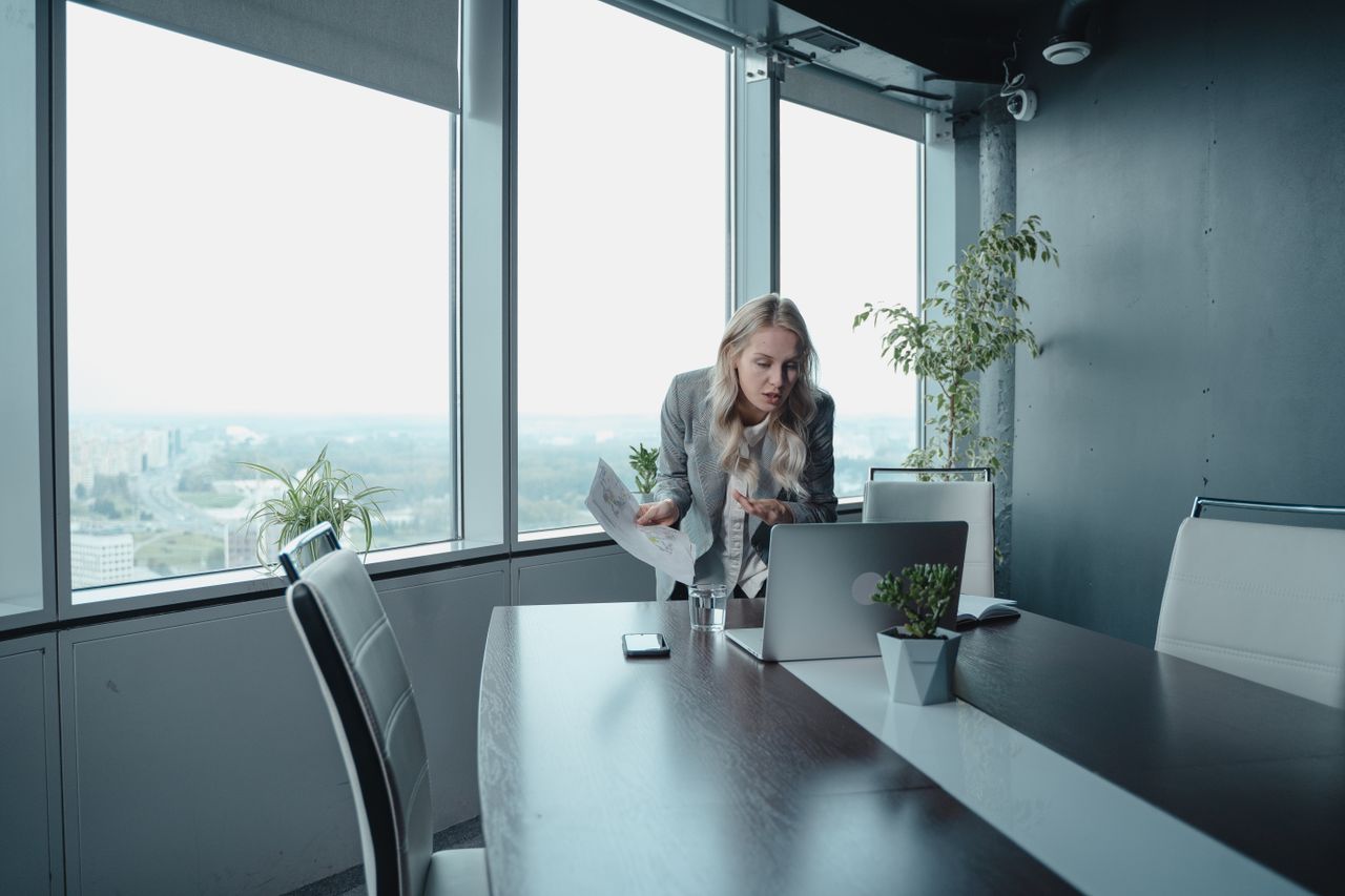 Professional woman engaged in a video call in a high-rise office with a scenic view.