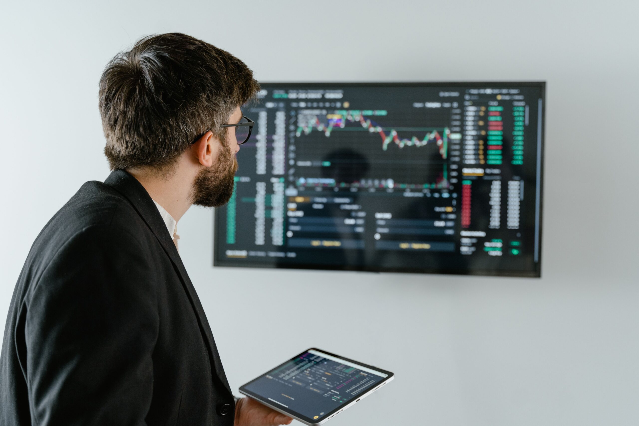 Data Scientist Career Guide: 5 Essential Steps for 2026 A businessman examines stock market data displayed on a monitor, holding a tablet.