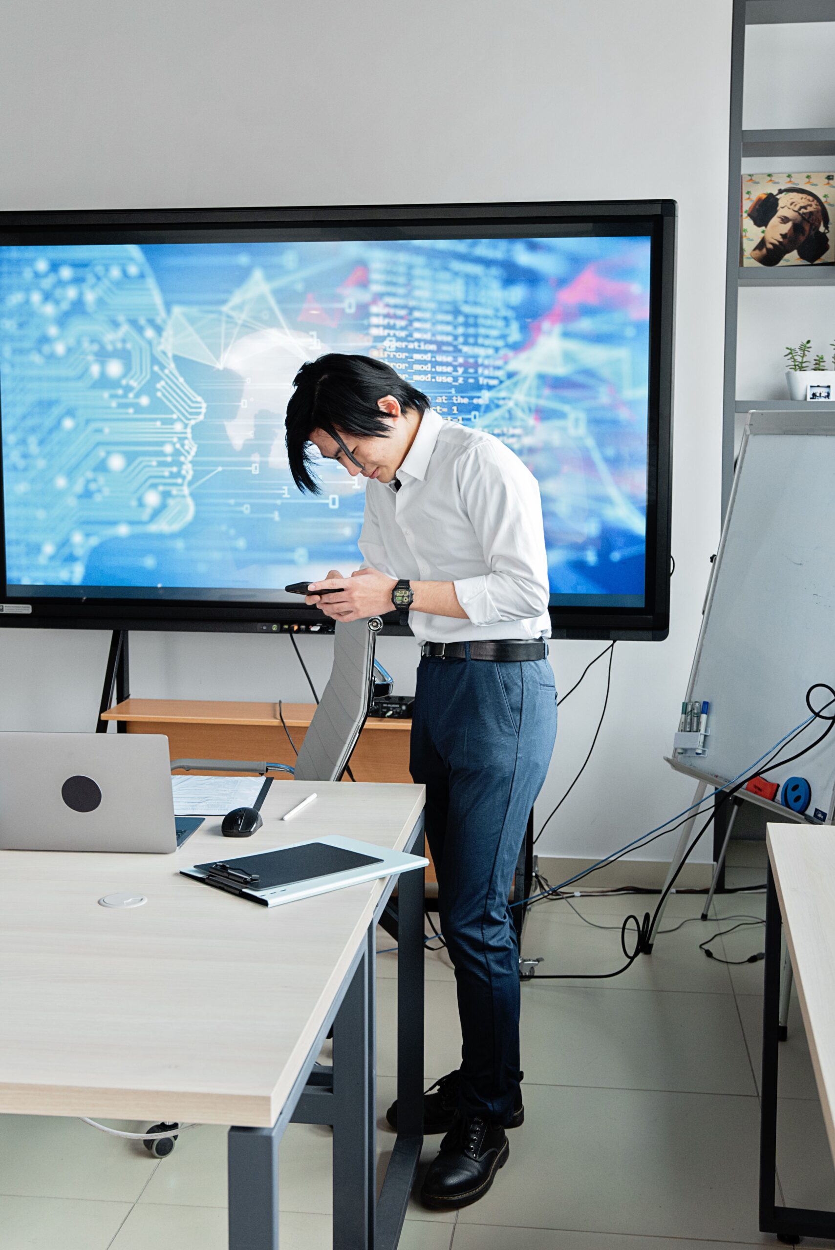 Understanding the ITI Executive Role: Responsibilities & Skills A man standing in an office checks his smartphone with a digital screen displaying AI graphics.